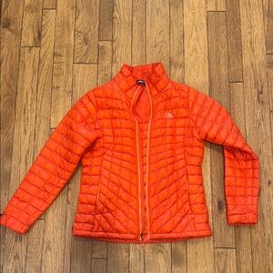 The North Face Orange Puffer Jacket with Chevron Quilting.